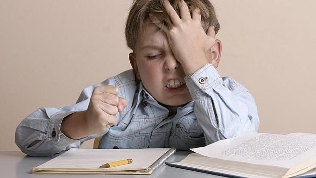 Frustrated boy slapping his forehead over an open schoolbook