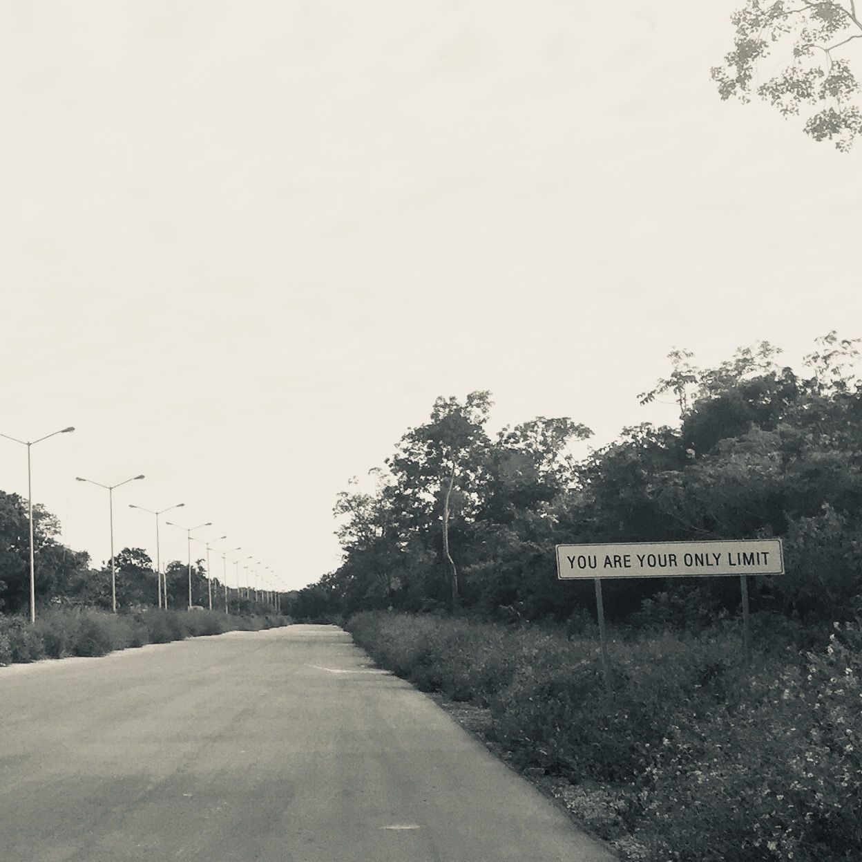 Empty road with a roadside sign reading "You are your only limit"