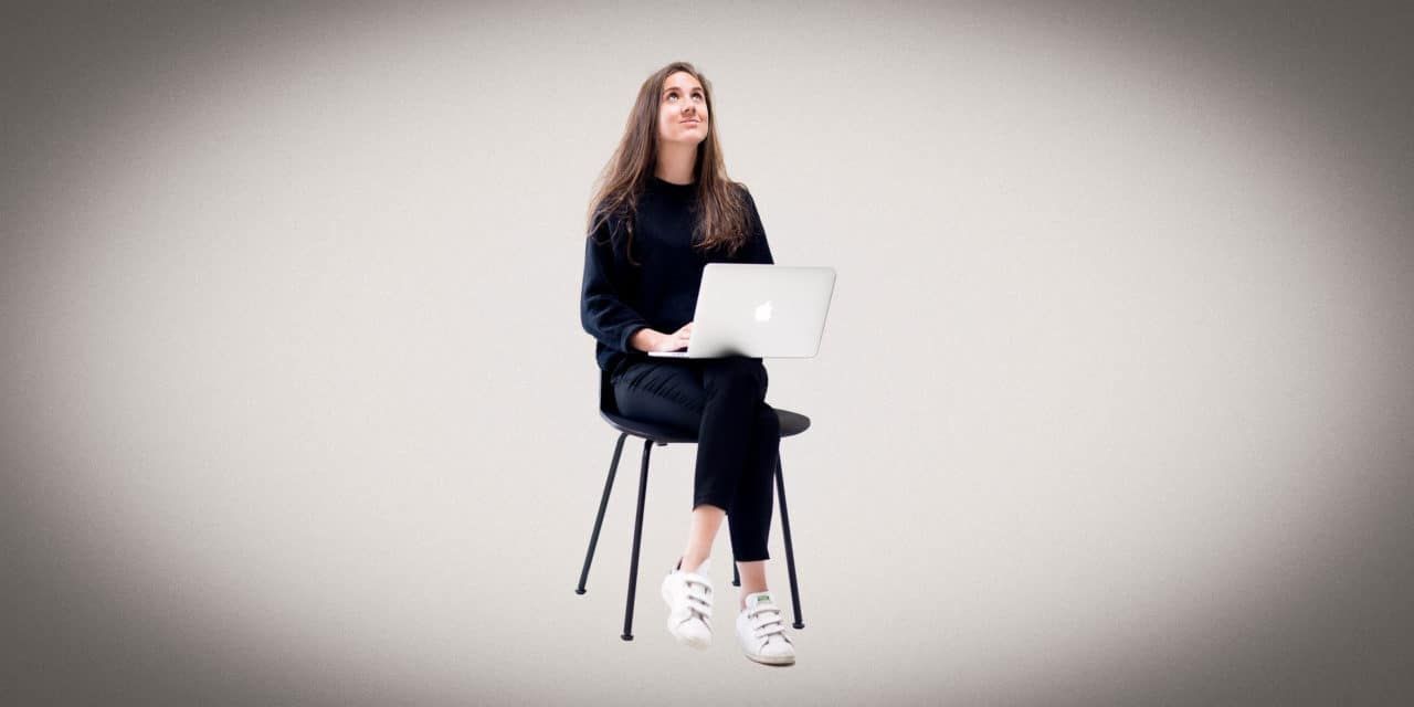 Marjolaine sitting on a chair with a laptop, looking upward